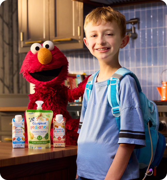 Boy wearing a backpack standing with Elmo
